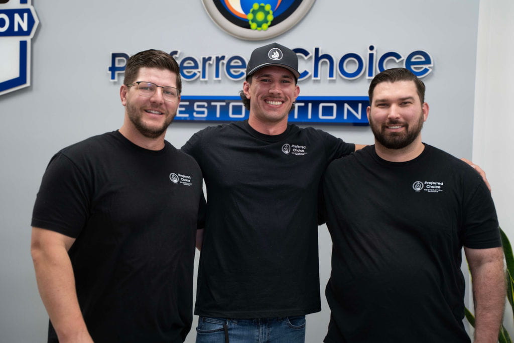 Preferred Choice Restoration owners standing in front of the company sign at the Phoenix office