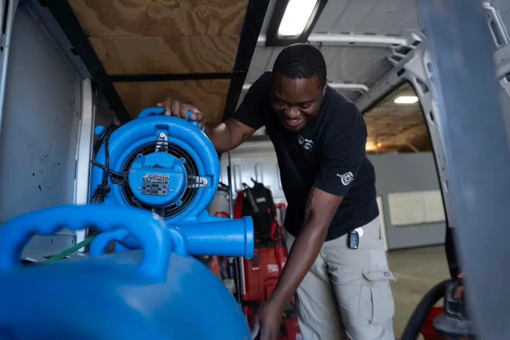 Air mover drying a water-damaged room after extraction.